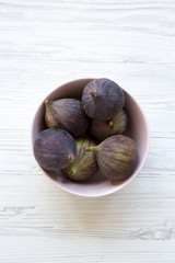 Fresh figs in a pink bowl on a white wooden background. Top view, overhead, from above. Close-up.