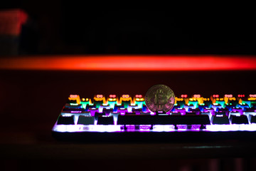 A metallic Bitcoin coin resting on a computer keyboard, symbolizing the fusion of digital currency and technology