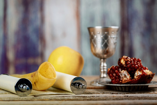 Torah, apple and pomegranate on wooden table over bokeh background
