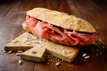 Sandwich with raw ham on wood background
