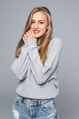 Portrait of a happy smiling woman in sweater with hands near face on the gray background