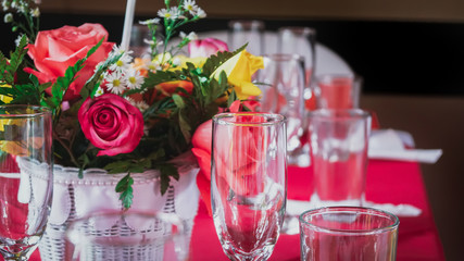 Glasses on a table decorated with a bouquet of colorful roses
