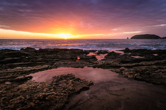 Wonderful sunset while cloudy sky reflects on sea water puddle