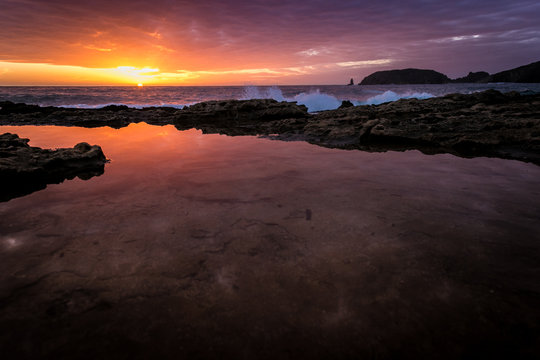 Wonderful sunset while cloudy sky reflects on sea water puddle