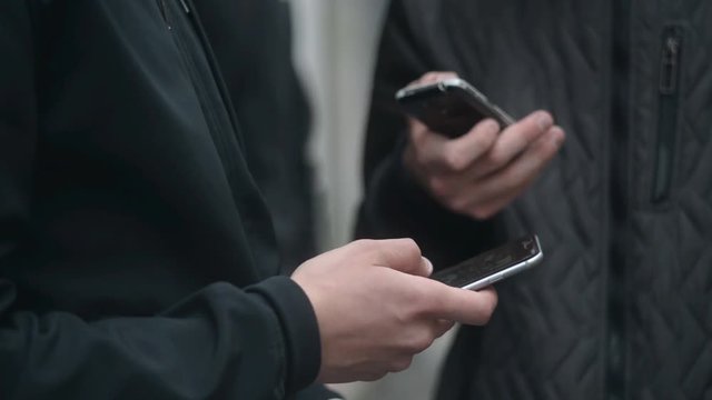 Two Men with mobile phone in hand chating in the street of Milan