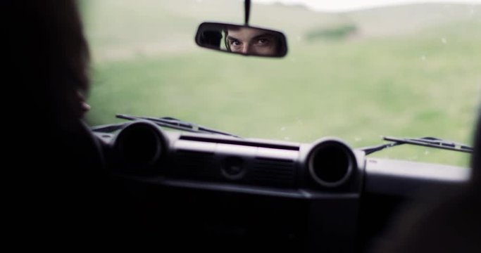 Reflection in mirror of young adult male on road trip