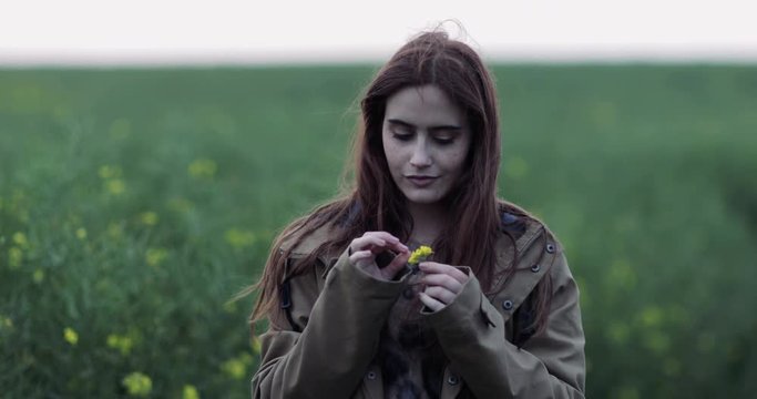 Millennial female picking a wild flower in a scenic landscape