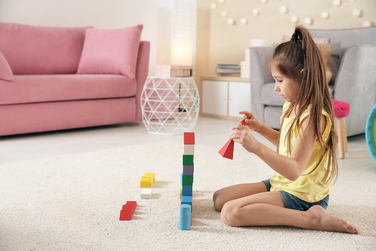 Cute little child playing with building blocks on floor, indoors
