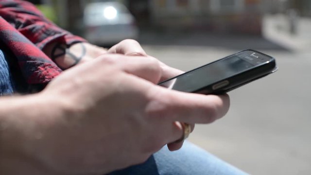 Mobile Cell Phone in the Hands of a Man - chating wrighting sms - in a city park