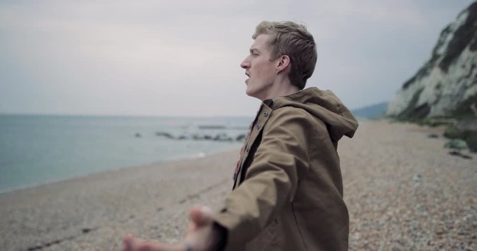 Millennial male enjoying the fresh air on a beach in winter