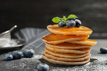Tasty pancakes with berries and honey on slate plate