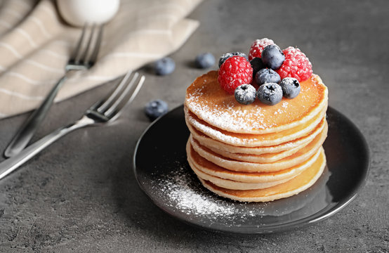 Tasty pancakes with berries and sugar powder on plate