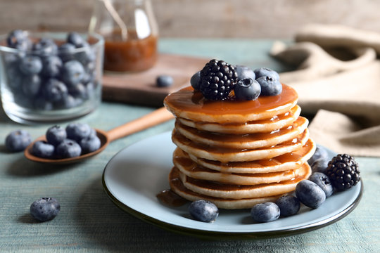 Tasty pancakes with berries and syrup on plate