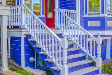 White outdoor banister blue house with red door