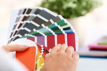 Woman with paint color palette samples on blurred background, closeup