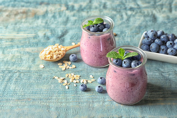 Tasty blueberry smoothie in jars, berries, oatmeal and space for text on wooden table