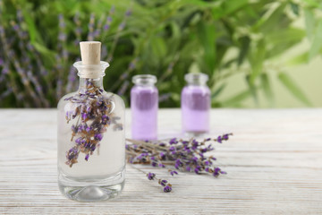 Obraz na płótnie Canvas Bottle with natural herbal oil and lavender flowers on table against blurred background. Space for text