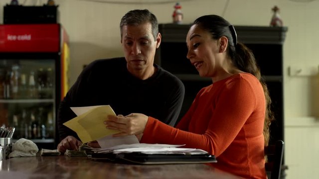 A stressed out married couple of hispanic descent discuss bills and expenses in their family Mexican food restaurant