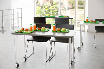 Trays with healthy food on table in school canteen