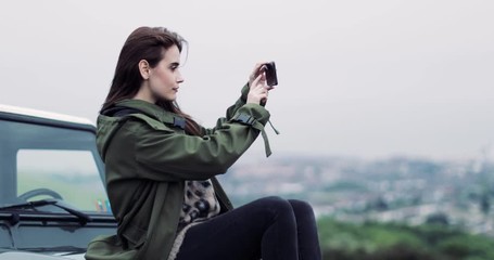 Millennial female taking photo of scenic landscape