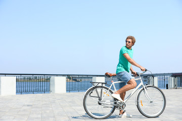 Fototapeta premium Handsome young man riding bicycle outdoors on sunny day