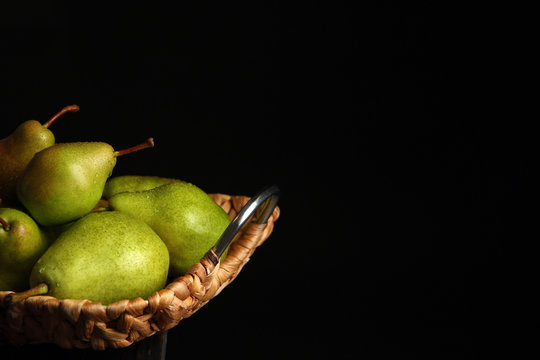 Tray with ripe pears on table against dark background. Space for text