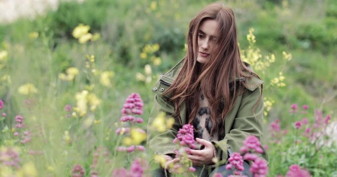 Millennial female touching a wild flower in a scenic landscape