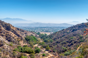 Fototapeta na wymiar Hiking and biking dirt trails in Southern California mountains with city in distance and blue sky for copy text