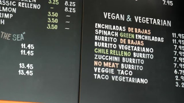 Slow panning shot of the extensive chalkboard menu inside a family owned Mexican restaurant