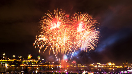 Naklejka premium Orange and golden fireworks in front of Quebec City during a summer festival.