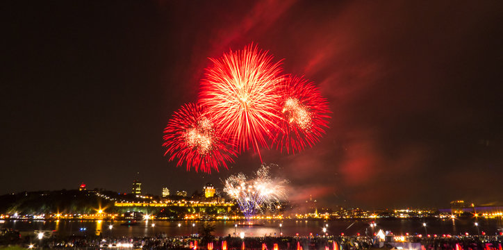 Red fireworks in front of Quebec City during a summer festival.