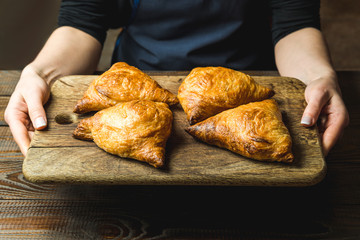 Uzbek national dish of samsa on a wooden board in the hands of a girl