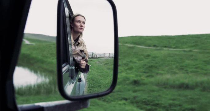 Reflection in mirror of young adult female on road trip