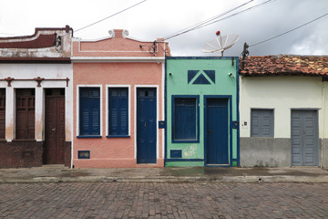 Pink house and green house with blue doors in cobblestone street, city of Andarai, interior of Bahia, Brazil