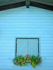 Shuttered window with flowers on a small Bavarian hut