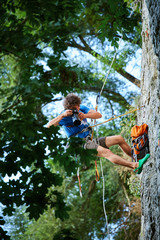 the photographer hangs on a rope on the cliff and shoots rock climbers