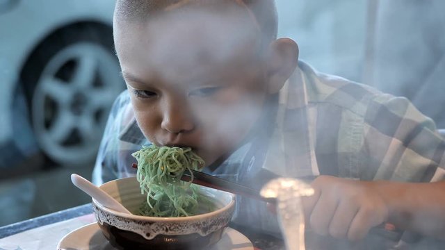 ..happy child eating delicious noodle in restaurant. Asian boys who have vision disabilities. Left eye is not visible from brain surgery. Come back to normal life Effect of the treatment. New life