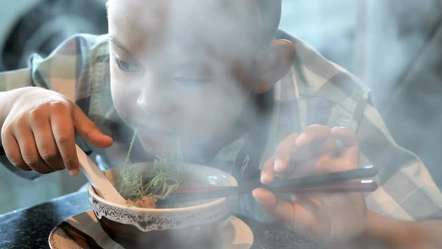 ..happy child eating delicious noodle in restaurant. Asian boys who have vision disabilities. Left eye is not visible from brain surgery. Come back to normal life Effect of the treatment. New life