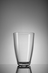 empty glass on grey background with reflection