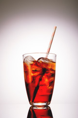 Cola in glass with ice on grey background