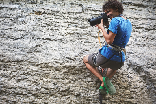 the photographer hangs on a rope on the cliff and shoots rock climbers