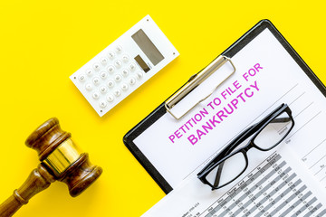 Petition to file for bankruptcy. Empty form ready to fill near calculator and judge gavel on yellow...