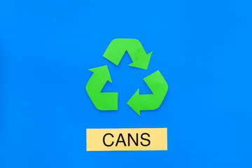 Types of matherial for reycle and reuse. Printed word cans near eco symbol recycle arrows on blue background top view copy space