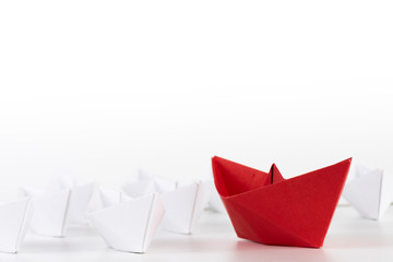 Leadership concept. red paper ship lead among white. One leader ship leads other ships.