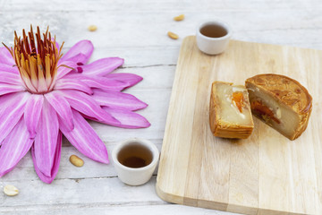 Fototapeta premium Flat lay of Mid Autumn festival Moon cake on old white table with pink water lily 