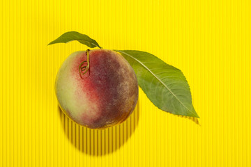 Ripe peach with leaves on a yellow background