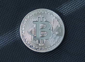 Obverse of metal bitcoin on blue fiber background. Crypto currency coin