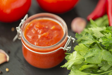 Adjika sauce made of pepper, garlic and spices on a black background. Sauce. Food background.