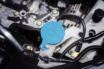 Windshield washer fluid cap with blue color in engine room of car, automotive part concept.