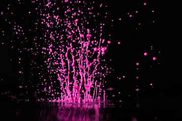 Magenta, pink  paint, ink splash on black background